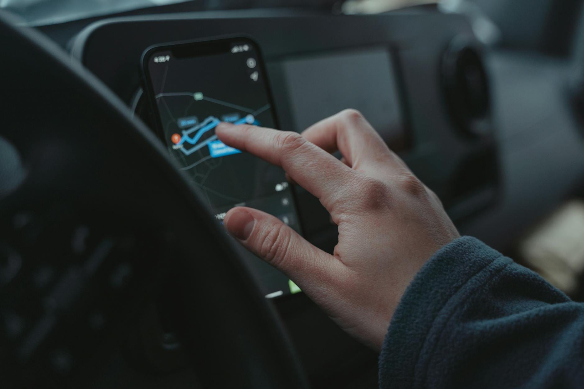 Dłoń ustawiająca trasę w aplikacji GPS na smartfonie w aucie