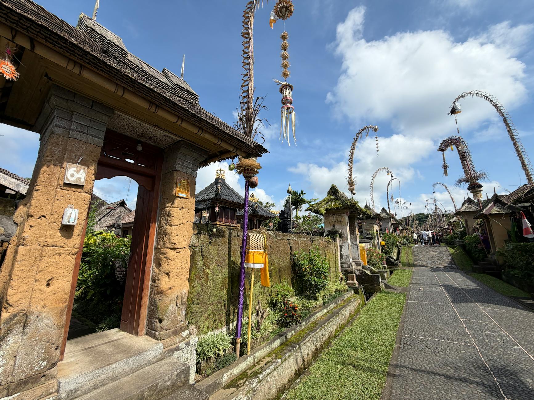 Tradycyjna balijska wioska z wysokimi dekoracjami penjor pod błękitnym niebem