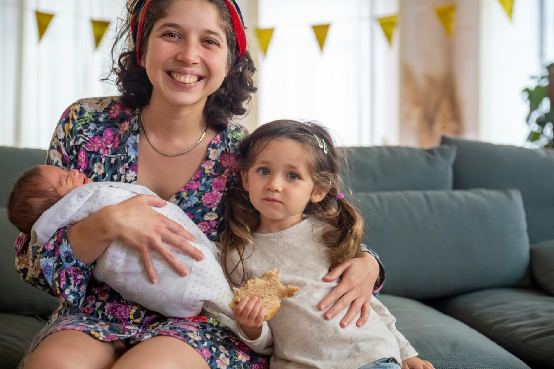 Mama z przedszkolakiem i młodszym dzieckiem siedzą razem na kanapie