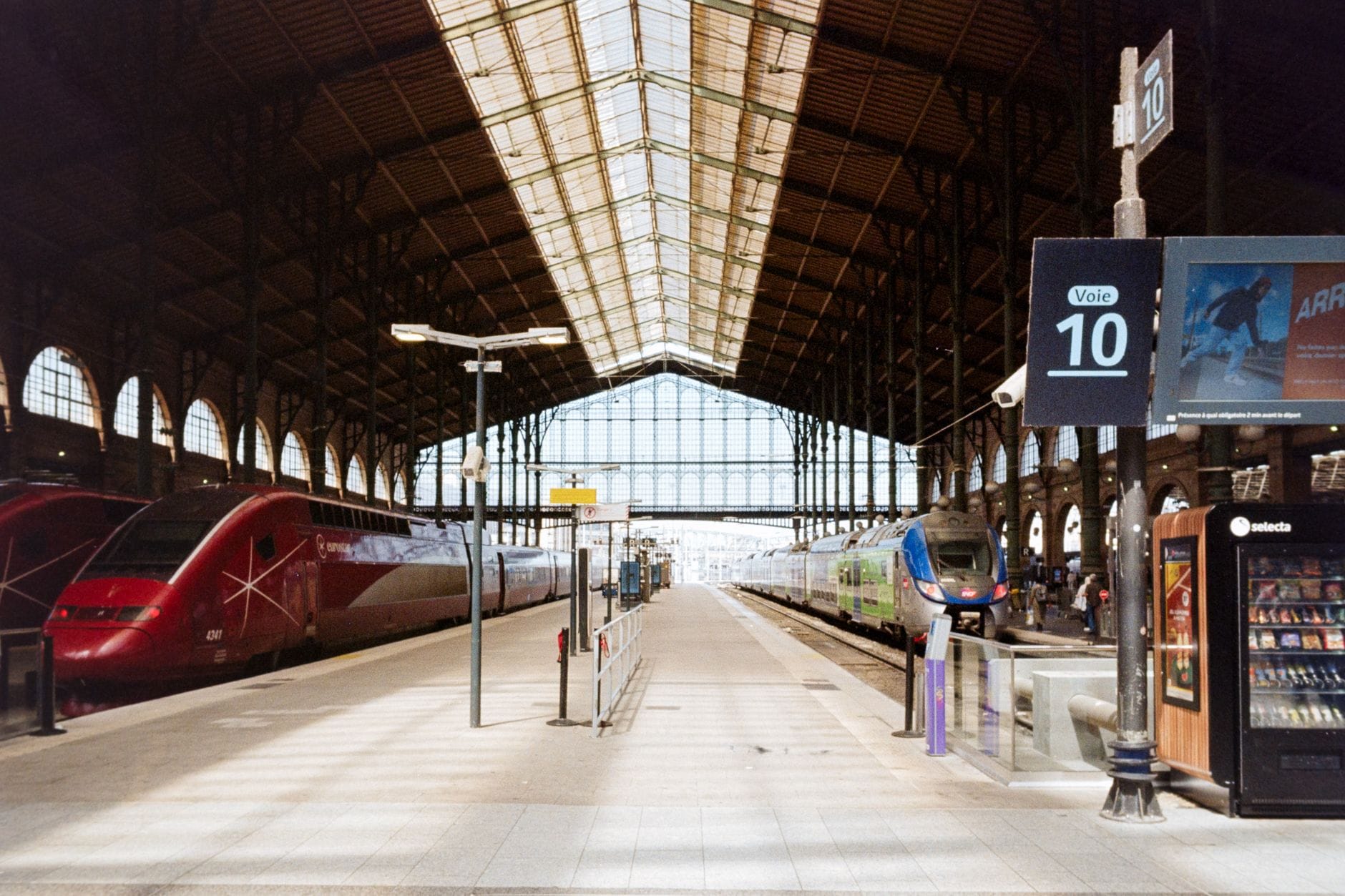 Wnętrze dworca Gare du Nord w Paryżu z pociągami pod szklanym dachem